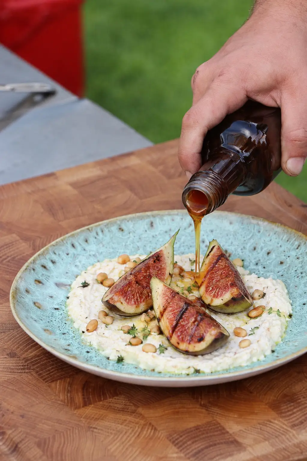 Goldener Thymianhonig wird über gegrillte Pfälzer Feigen auf cremigem griechischem Ziegenkäse gegossen.