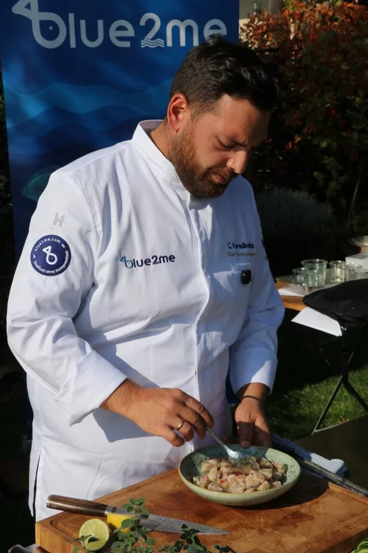 Mietkoch Chris Beim Anrichten Mietkoch Chris in seiner weißen Kochjacke richtet konzentriert ein frisches mediterranes Seafood-Gericht für Gäste an.